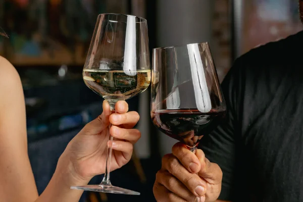 Two glasses of wine, white and red, raised in a toast